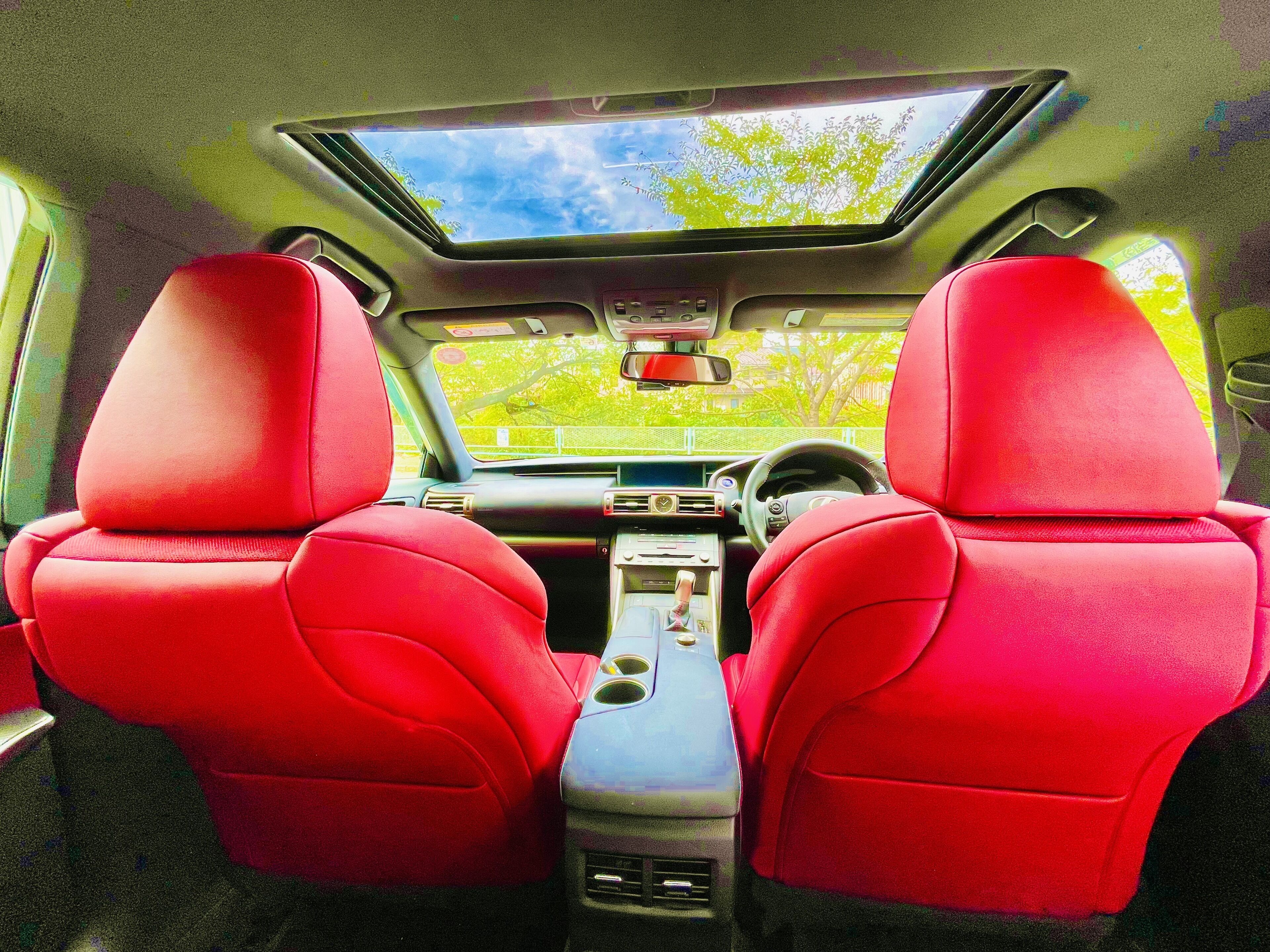 A car interior with two red leather seats, a sunroof, and a central console with a steering wheel.