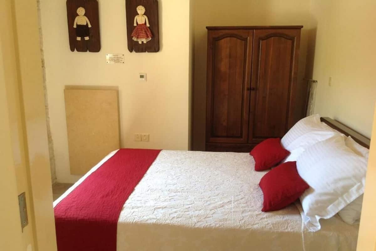 A bedroom with a bed, a wooden wardrobe, and two wall decorations.