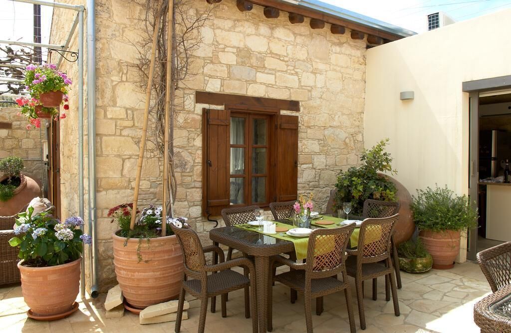 An outdoor patio with a stone wall, a wooden door, and a table set for dining.