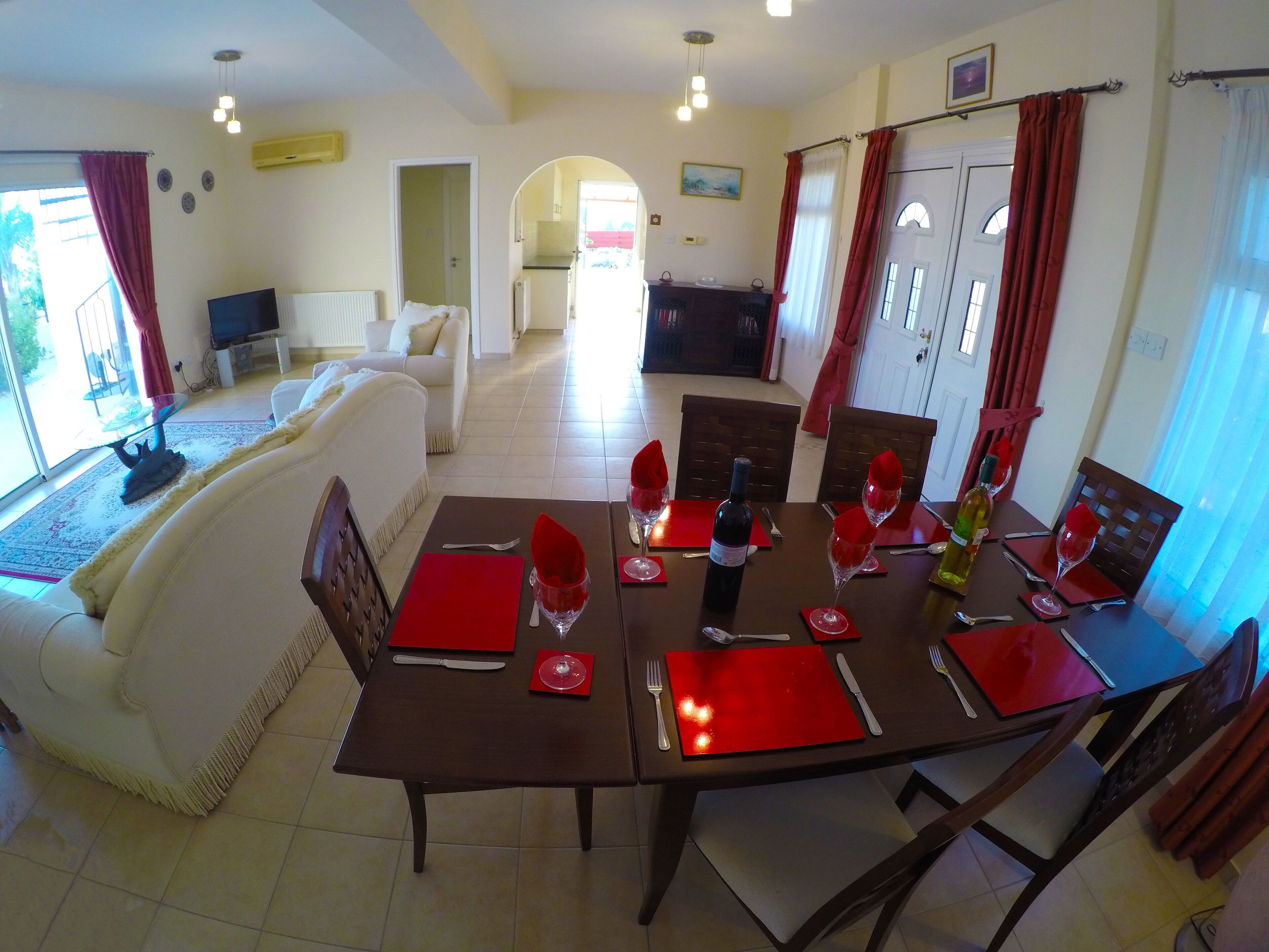 Un coin repas avec une table dressée pour quatre personnes, un canapé et un téléviseur en arrière-plan.