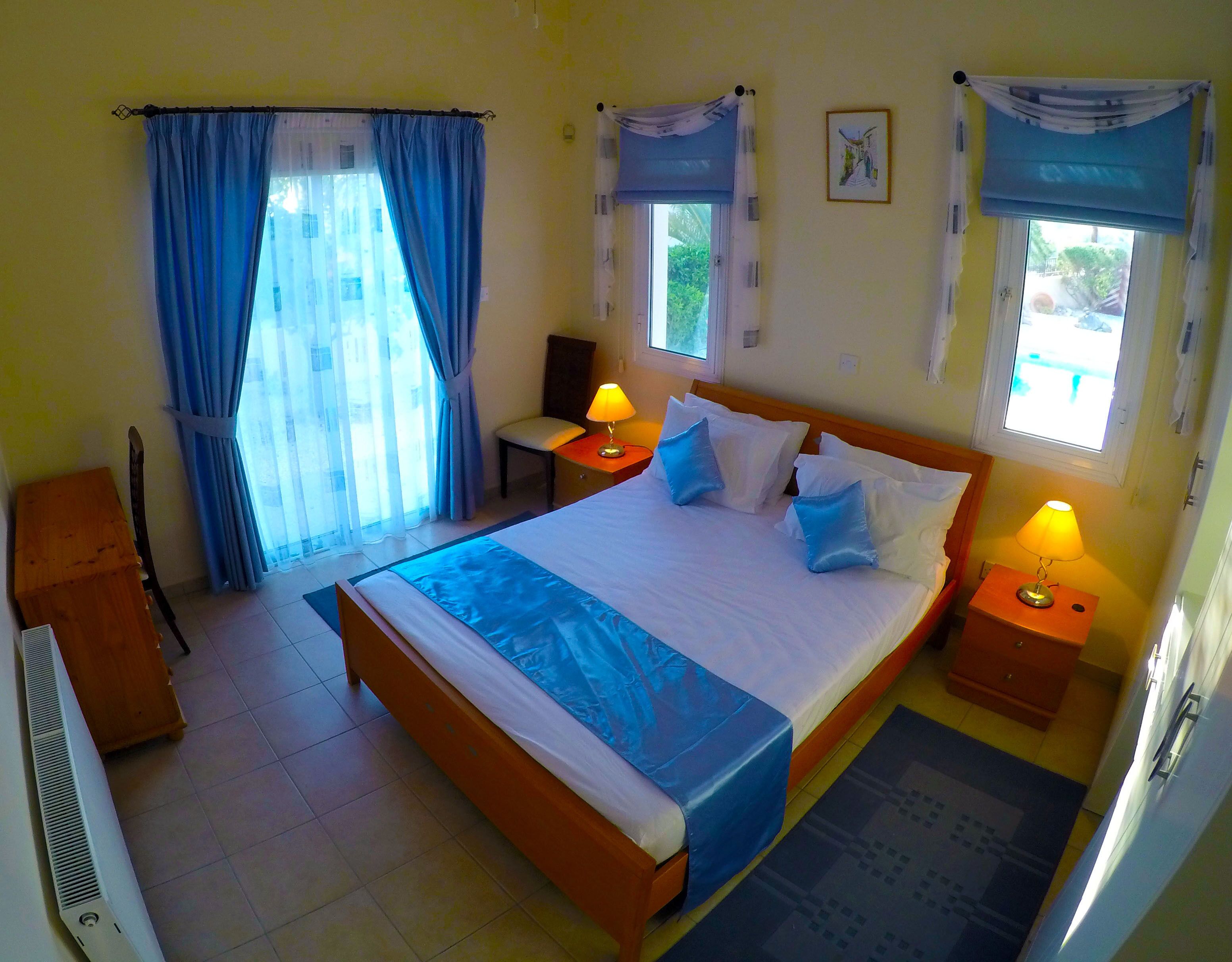 Une chambre  à coucher avec un grand lit, deux tables de chevet avec des lampes, une chaise, un bureau et un radiateur.
