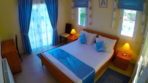 Quarto com cama grande, duas mesas de cabeceira com abajures, uma cadeira, uma escrivaninha e um radiador.