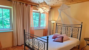 Une chambre à coucher avec un lit, des rideaux, une fenêtre et une table de chevet.
