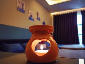 Une bougie allumée dans un porte-bougie en verre en forme de cœur, posée sur une table.