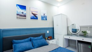 Un dormitorio con cama, escritorio y armario. Hay tres cuadros en la pared.