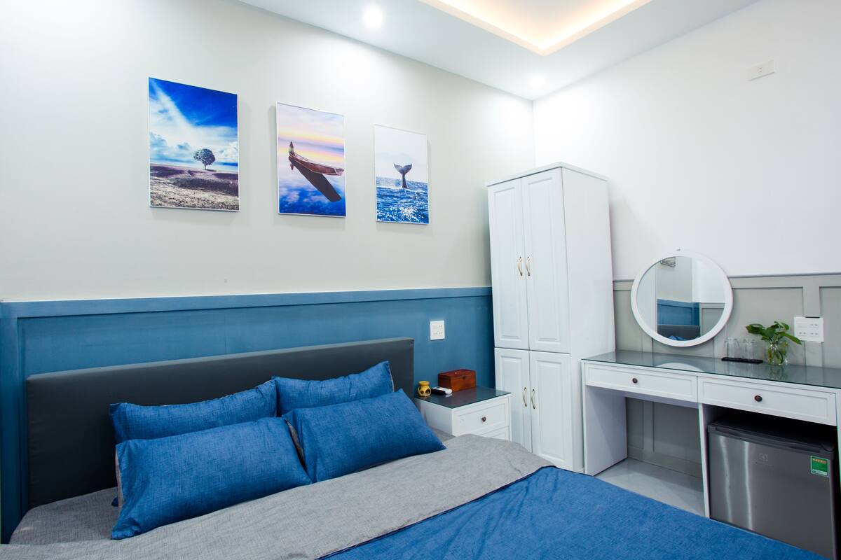 A bedroom with a bed, a desk, and a wardrobe. There are three framed pictures on the wall.