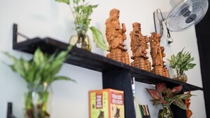 Una estantería con figuritas de madera, un abanico y libros.