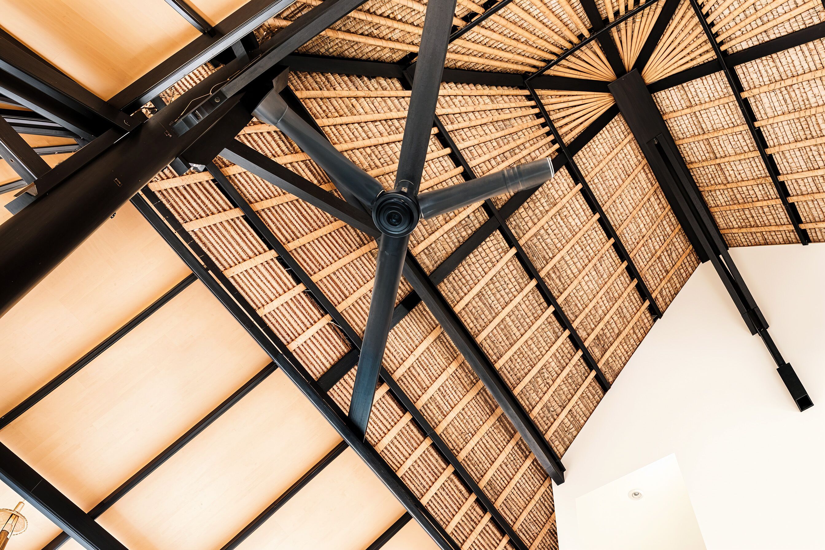 A ceiling with a geometric metal framework and a woven bamboo pattern.