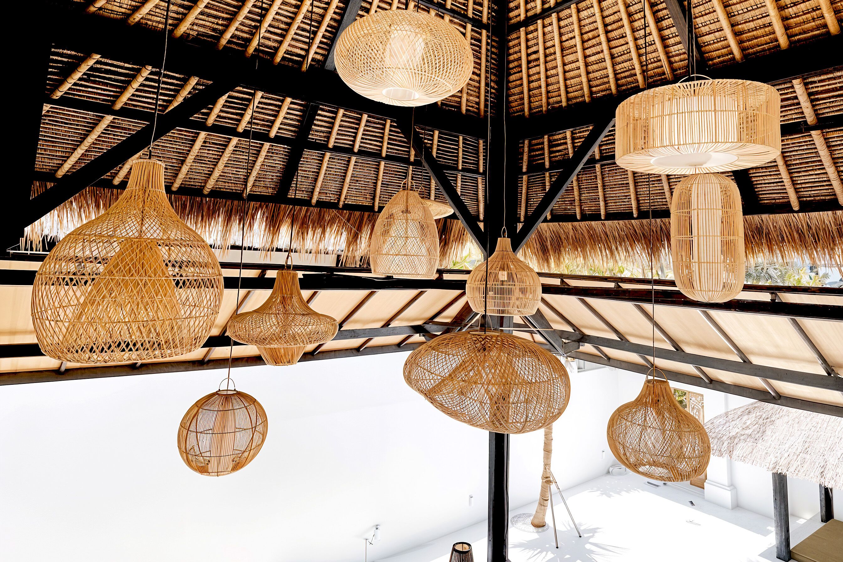 A ceiling with multiple woven light fixtures and a thatched roof structure.