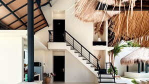 A spacious living area with a staircase, a pool, and a thatched ceiling. - Villa de Malicott (Seminyak)