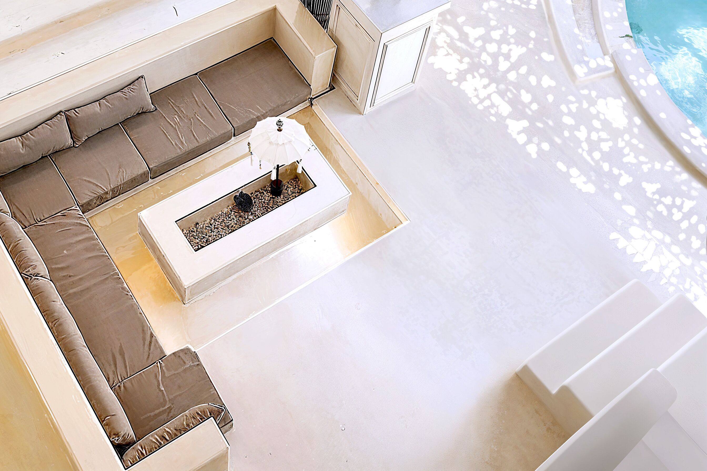 A poolside area with a white outdoor seating area, a small table with a decorative item, and a pool with a white deck.