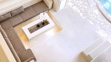 A poolside area with a white outdoor seating area, a small table with a decorative item, and a pool with a white deck.