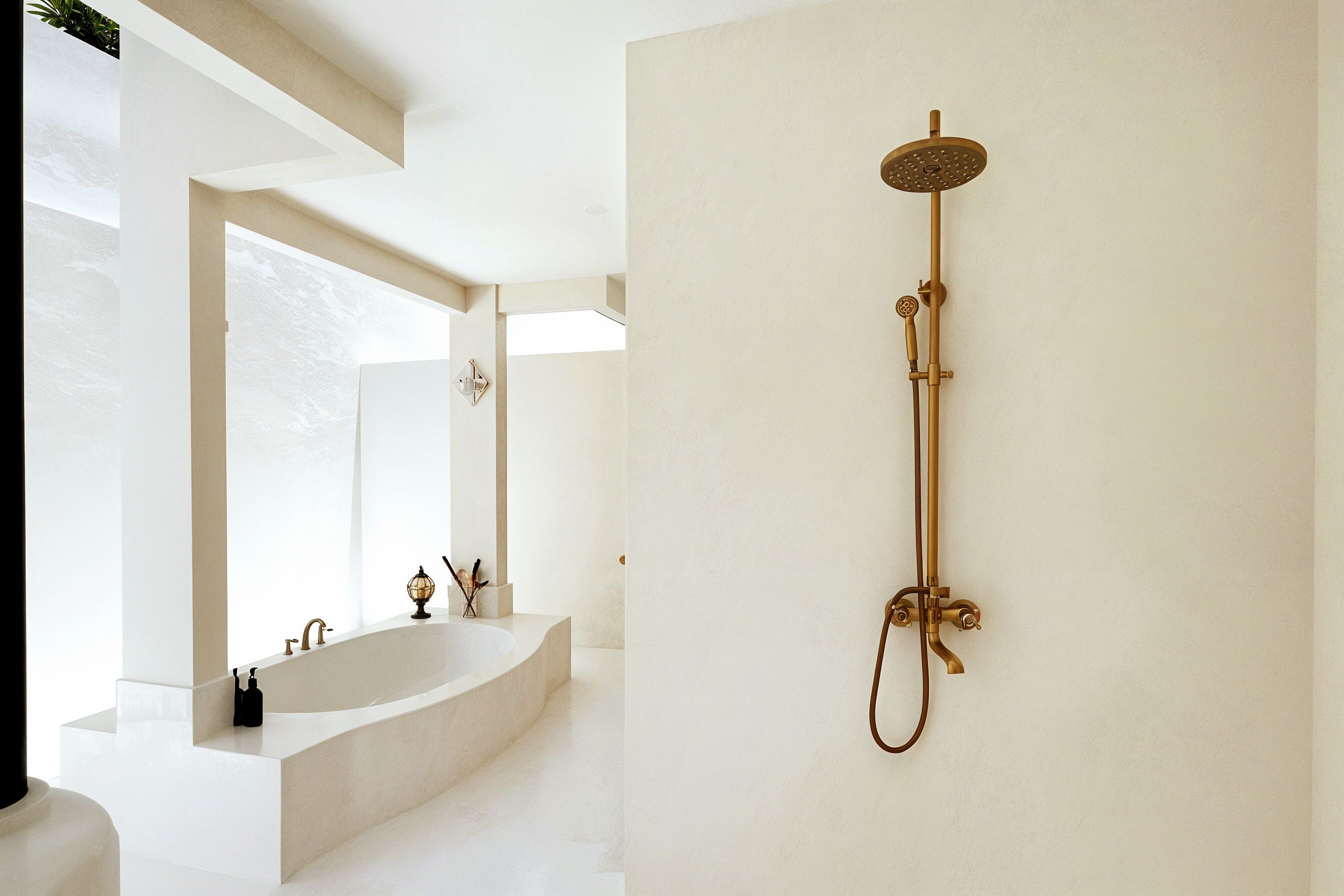 A modern bathroom with a freestanding bathtub, a wall-mounted showerhead, and a large mirror.