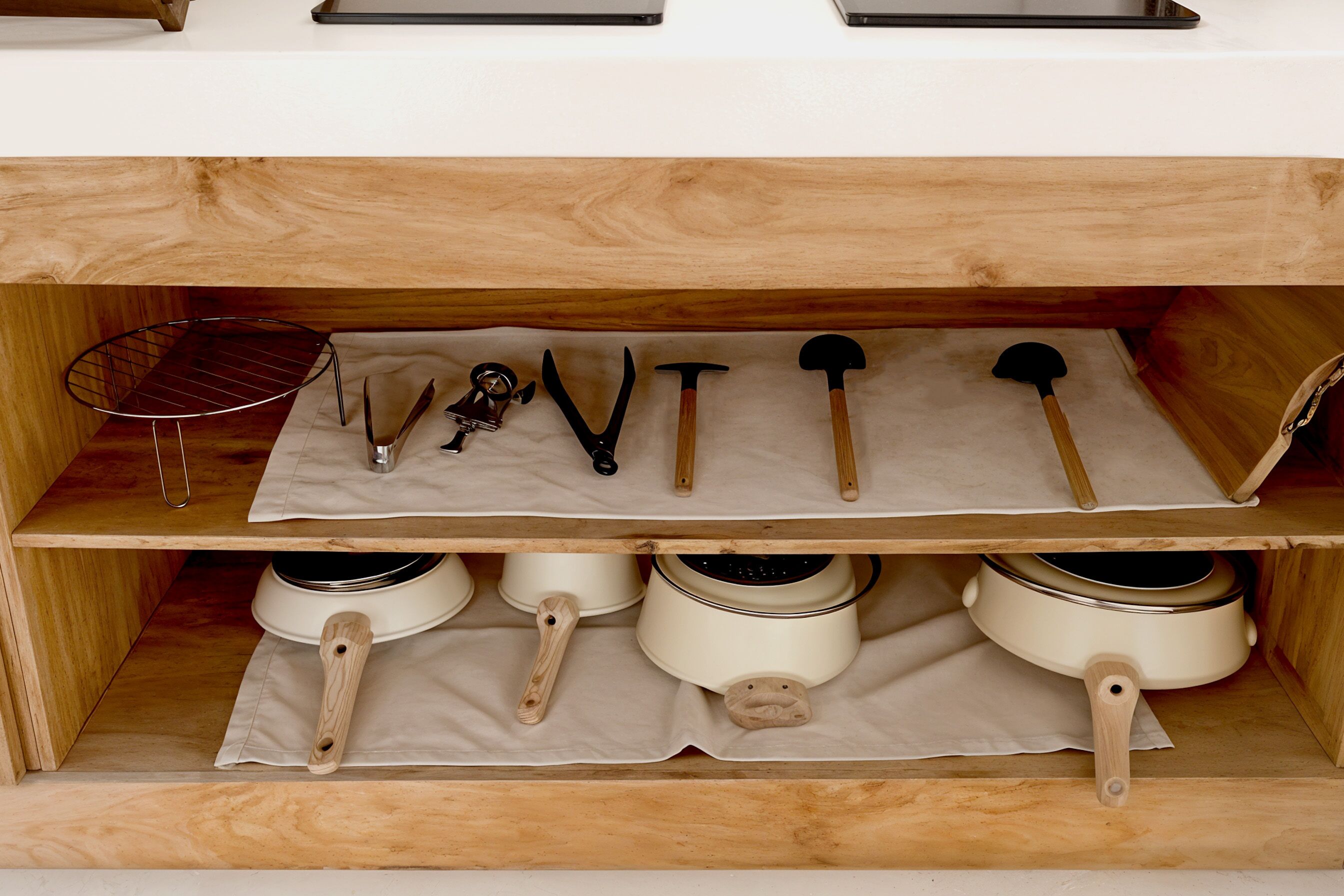 Una cocina con repisas de madera que sostienen ollas, sartenes y utensilios.
