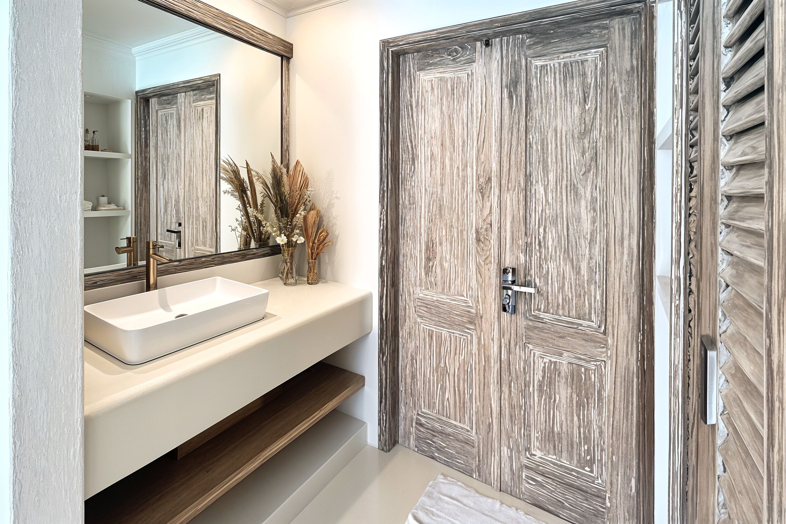 A bathroom with a white sink, mirror, and wooden door.