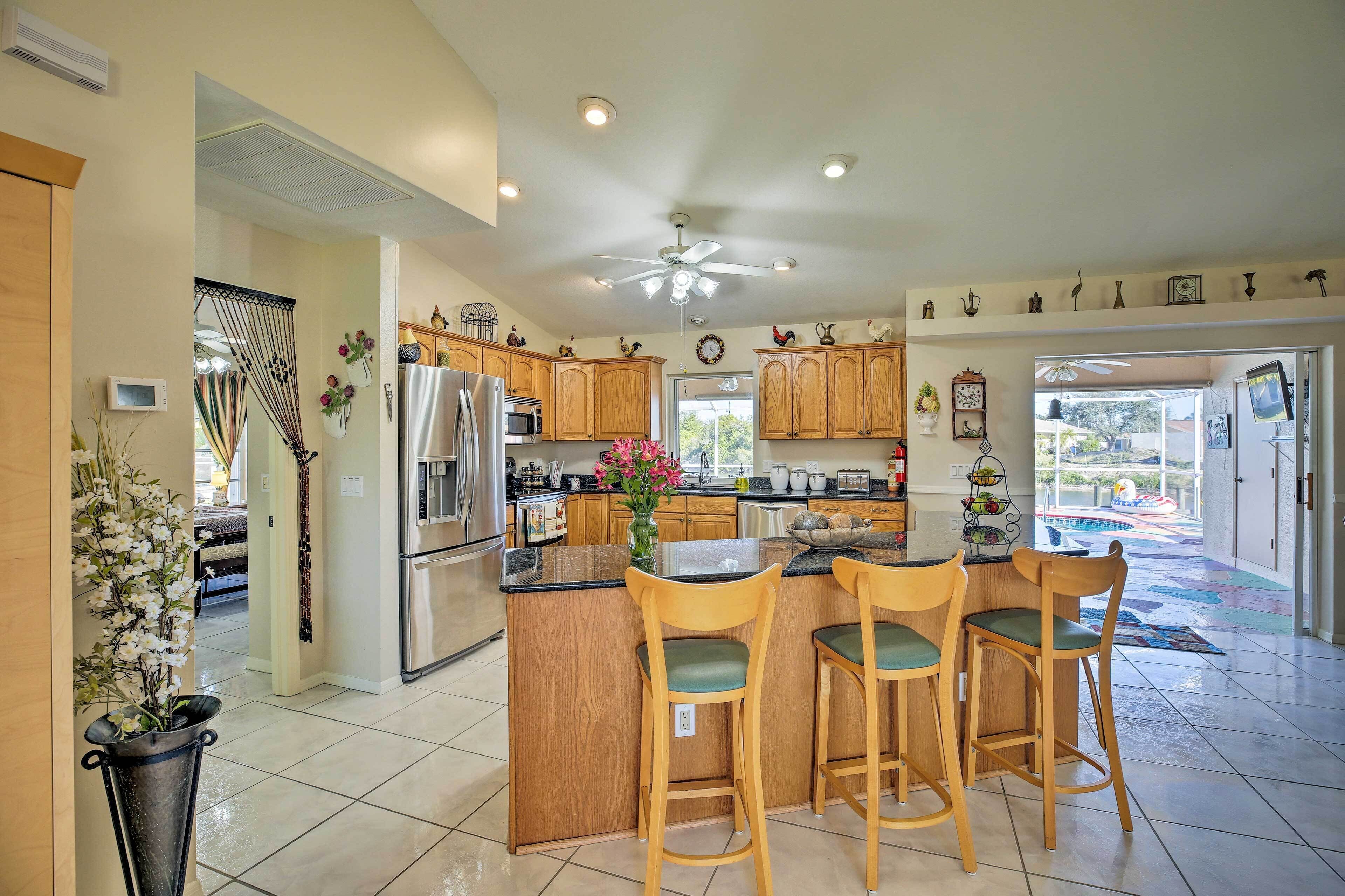 A spacious kitchen with wooden cabinets, a central island with bar stools, and a ceiling fan.
