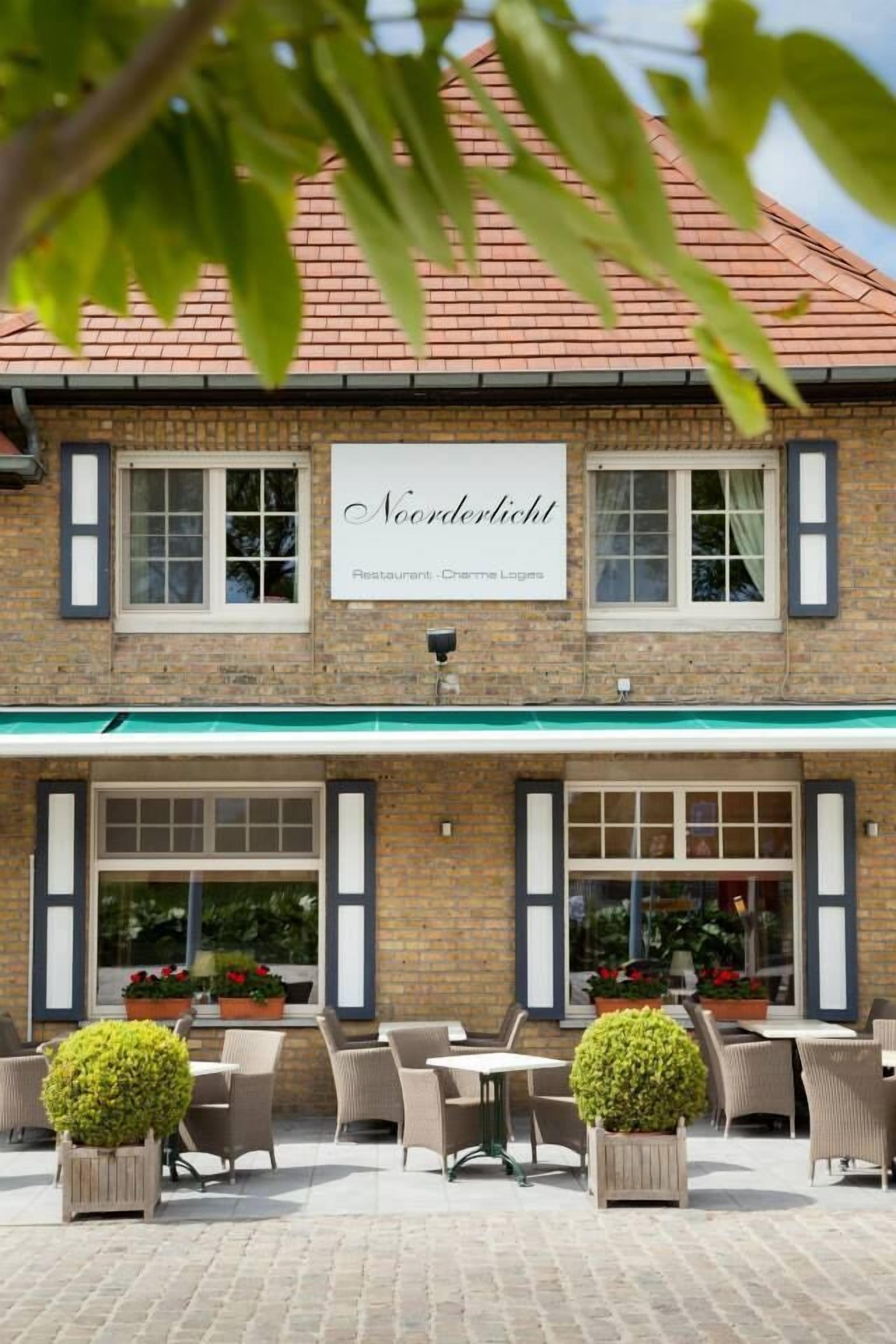 A brick building with a sign reading "Noorderlicht Restaurant - Charme Loges."