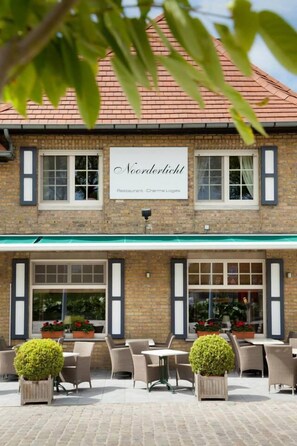 A brick building with a sign reading "Noorderlicht Restaurant - Charme Loges."