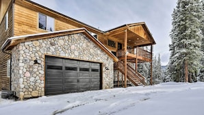 Eine Blockhütte mit Steinaußenwand, einer Garage und einem Holzbalkon.