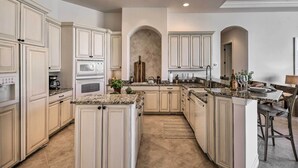 A spacious kitchen with high ceilings, built-in cabinetry, and a central island.