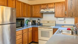 A kitchen with wooden cabinets, a stainless steel refrigerator, a microwave, a coffee maker, a toaster, and a stove. - 'The Overlook' in Massanutten’s All Season Resort (McGaheysville)