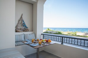 A balcony with a dining table set for breakfast, a sofa, and a view of the sea. - B4B Sea n' City (Zakynthos)