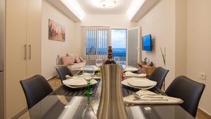 A dining area with a glass table, chairs, and a view of the sea through the window. - B4B Sea n' City (Zakynthos)