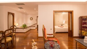 A spacious living area with a wooden floor, a dining table with chairs, a red upholstered chair, and a small table with a decorative item. - B4B Sea n' City (Zakynthos)