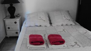A neatly made bed with white linens and two red towels placed on the foot of the bed. - Studio La Douloire (Pernes-les-Fontaines)