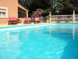 Une piscine avec des chaises longues et une clôture.