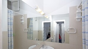 Un baño con lavamanos, espejo, ducha e inodoro.
