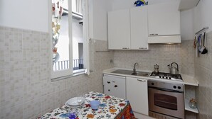Una cocina compacta con armarios blancos, una estufa a gas y un lavamanos.