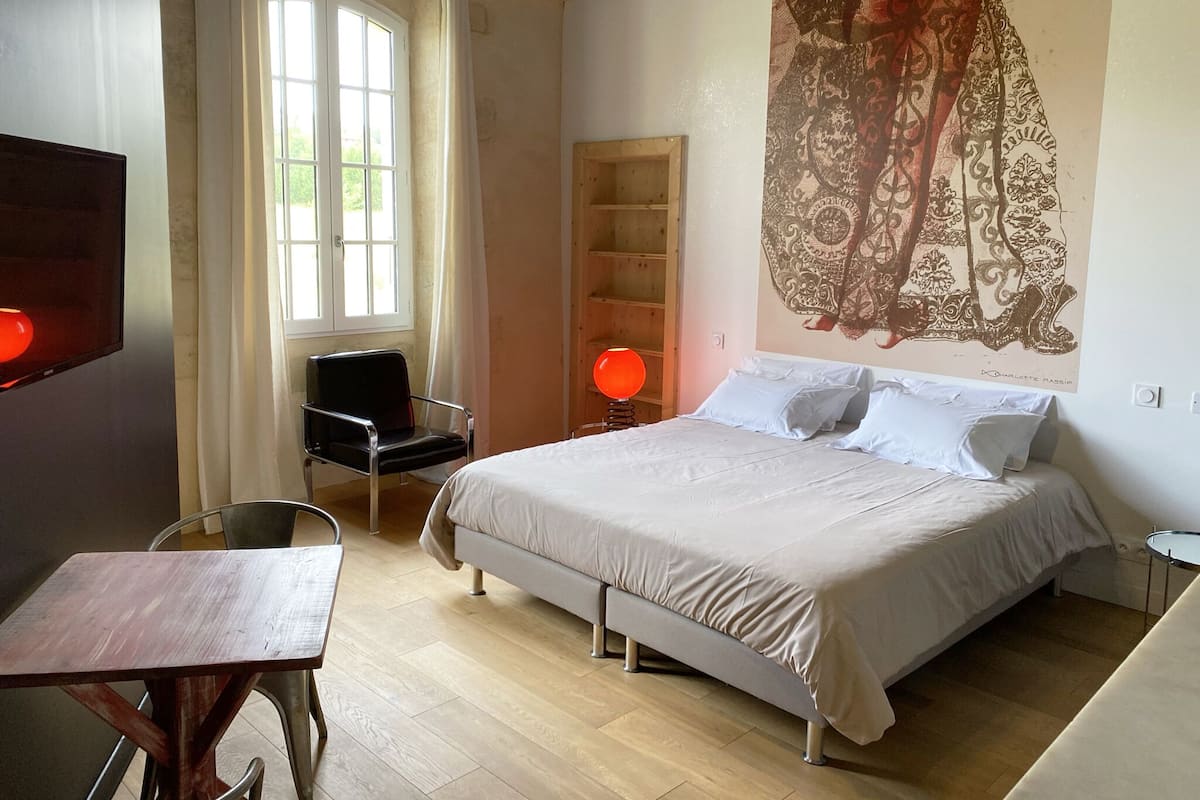 Un dormitorio con cama, una silla, una mesa y un mural grande en la pared.