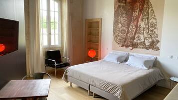 Un dormitorio con cama, una silla, una mesa y un mural grande en la pared.