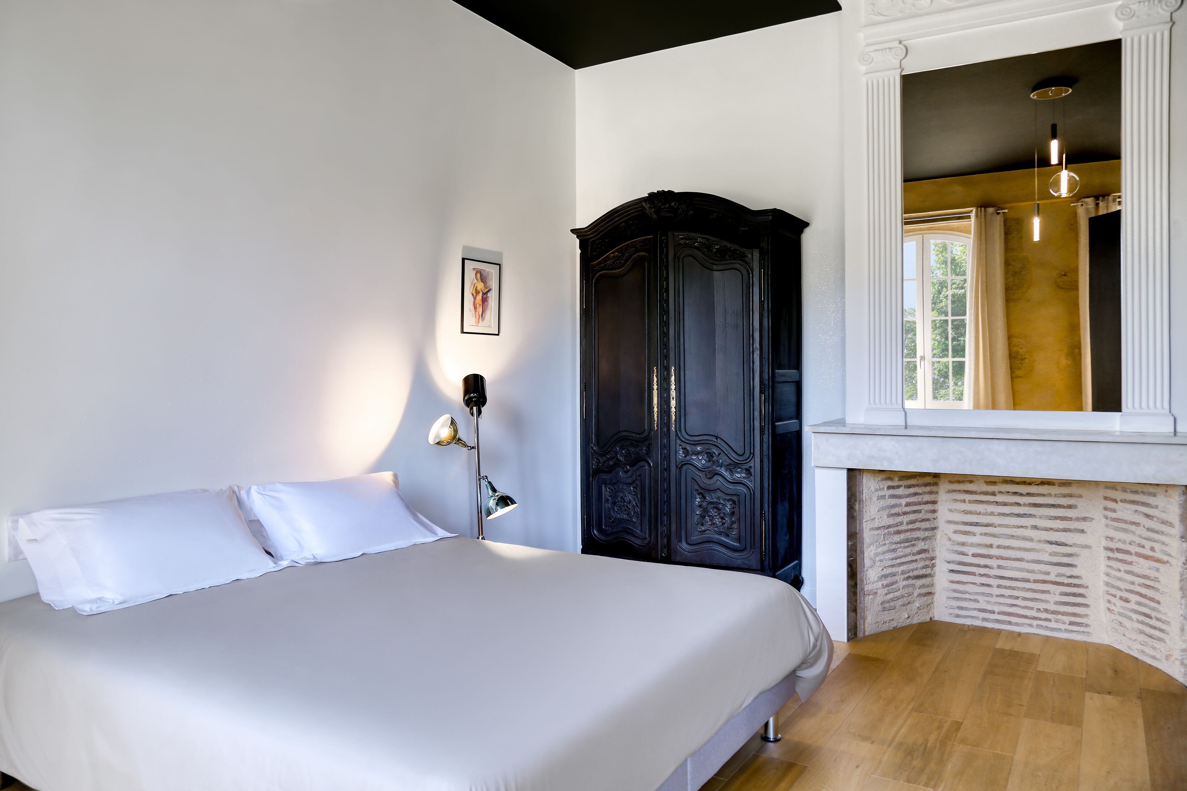 A bedroom with a bed, a dark wooden wardrobe, and a window with curtains.