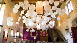 L’intérieur d’un hôtel avec un plafond en bois, des lanternes en papier blanches, un mur violet et un escalier.