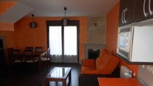 A living room with a fireplace, orange furniture, and a television. - Stone Cottage III (Canencia)