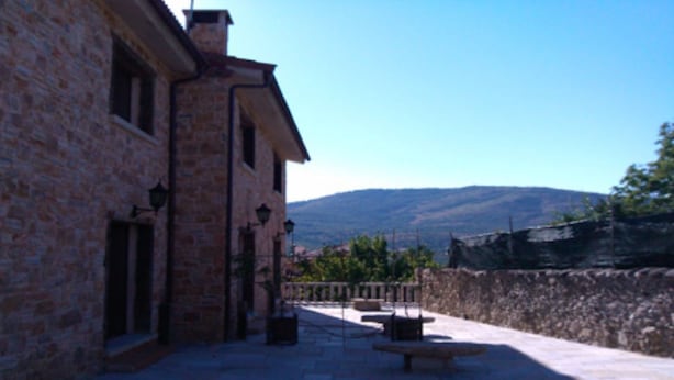 A stone building with a patio area, outdoor seating, and a view of mountains. - Stone Cottage III (Canencia)