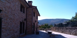 Un bâtiment en pierre doté d’un patio, d’un espace extérieur aménagé pour s’asseoir et offrant une vue sur les montagnes.