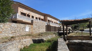 A stone building with a balcony, a covered outdoor area, and a stone wall. - Stone Cottage III (Canencia)