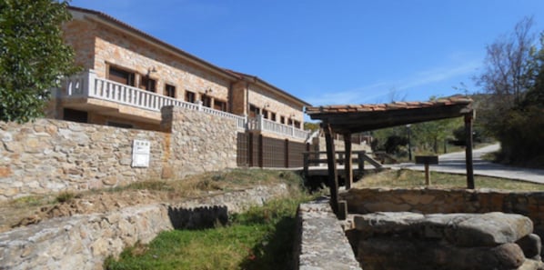 Un bâtiment en pierre doté d’un balcon, d’un espace extérieur couvert et d’un mur en pierre.