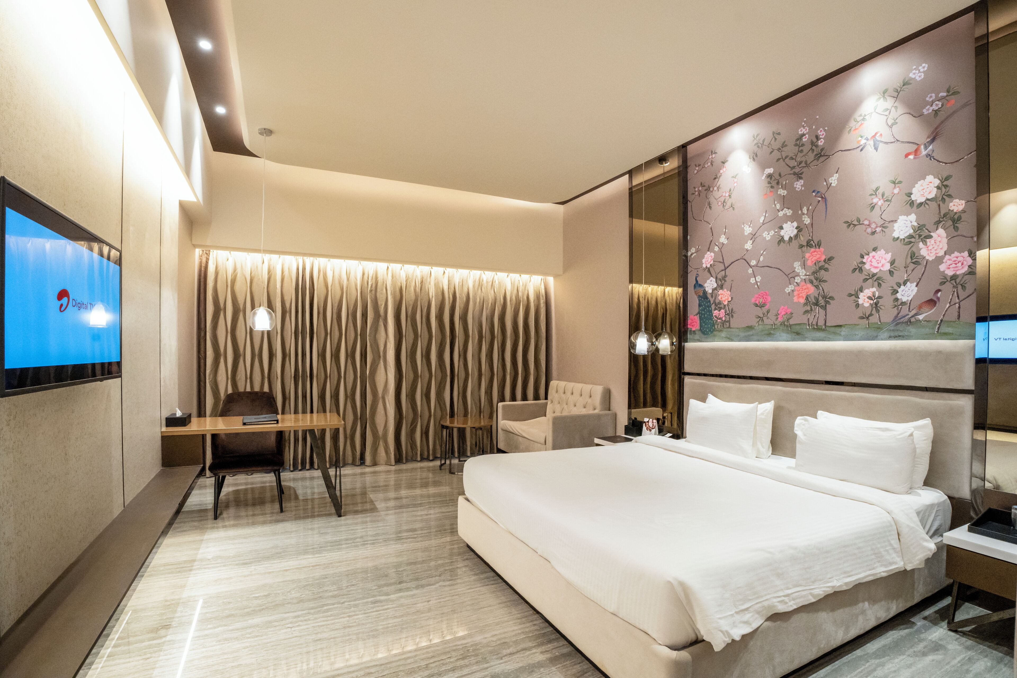 A modern hotel room with a large bed, a desk, and a TV.
