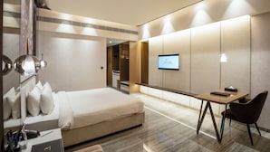 A modern hotel room with a bed, desk, chair, and a TV on the wall. - Seven Eleven Club (Mumbai)
