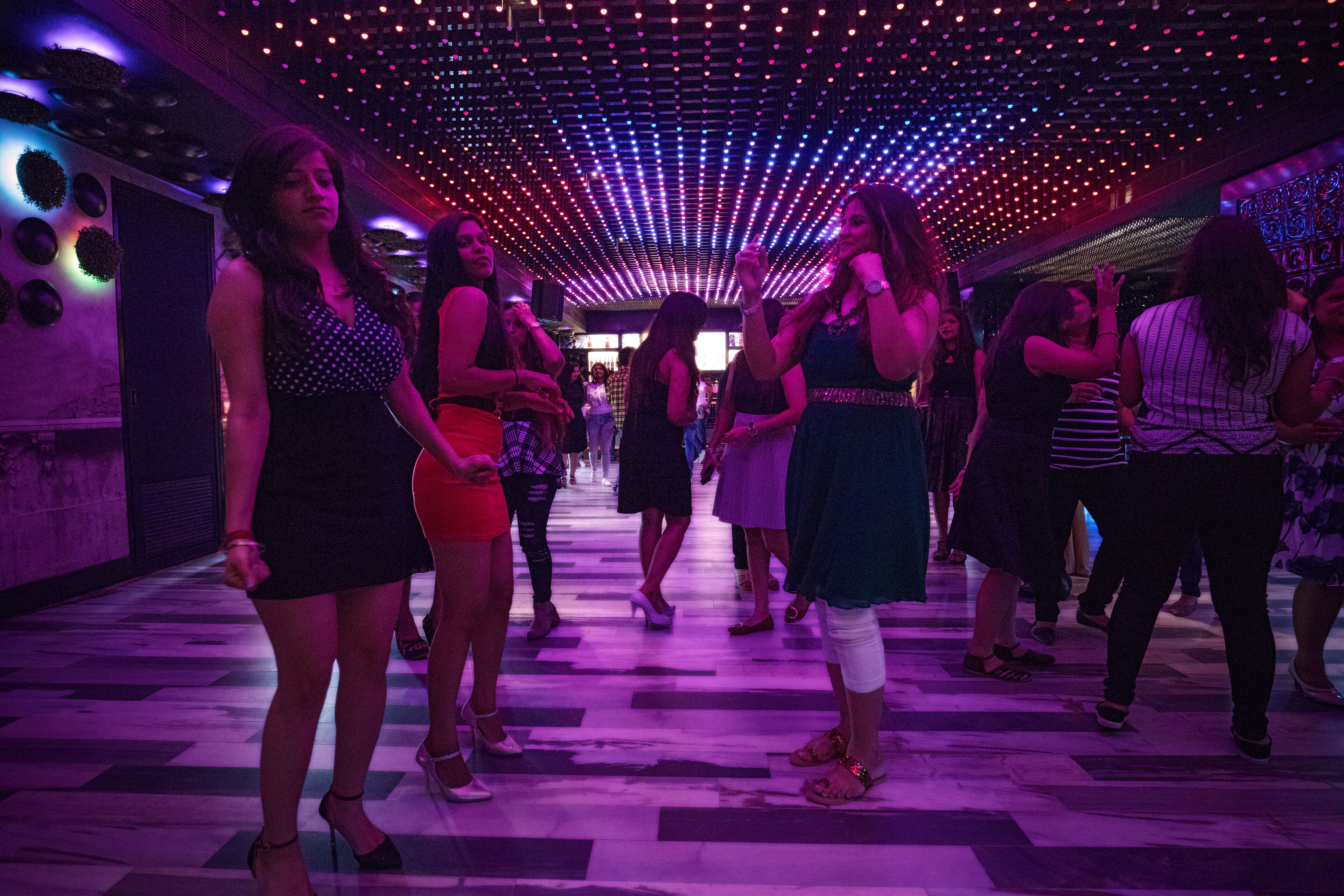 A crowded indoor space with a patterned floor and a ceiling with numerous lights.
