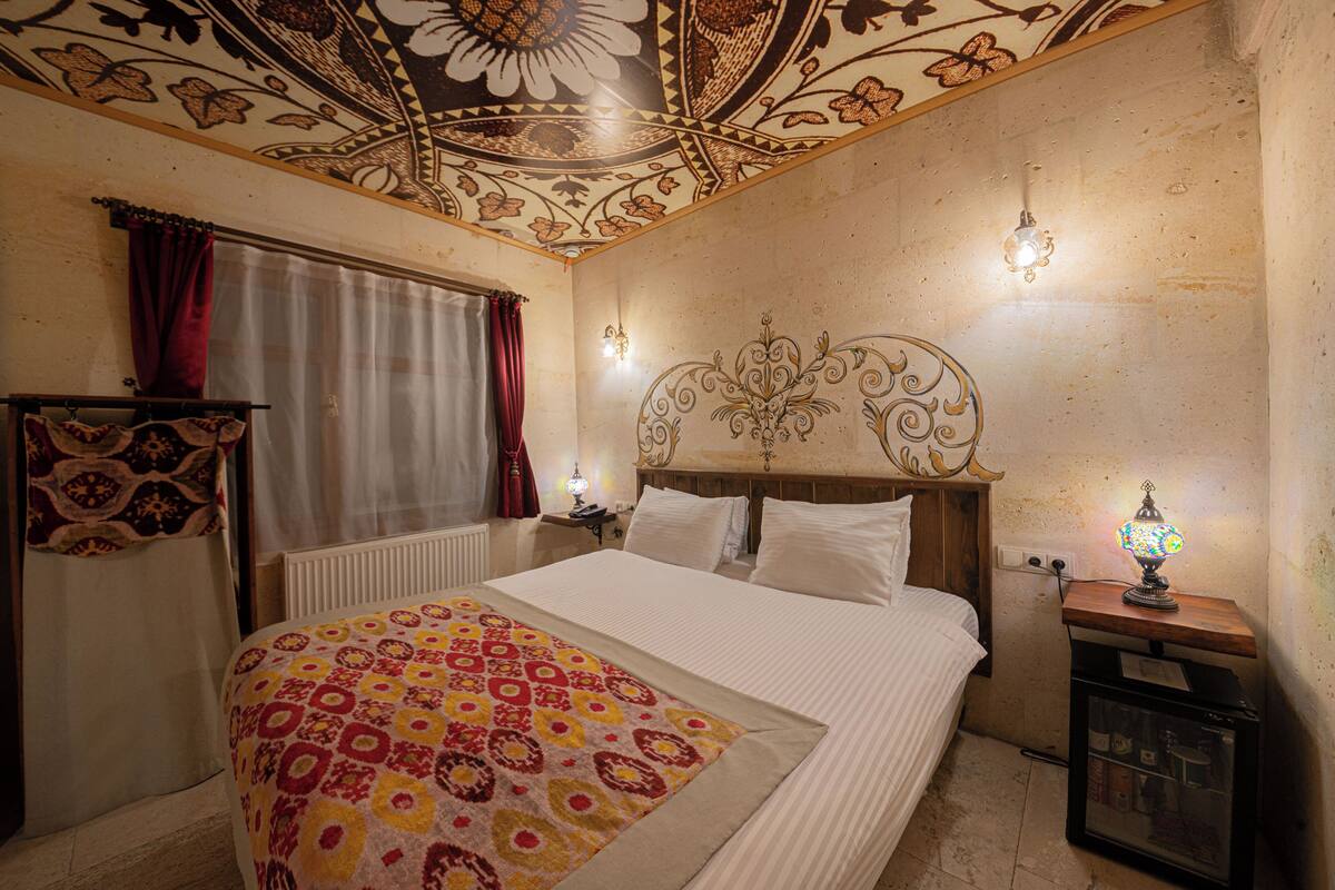 Um quarto com um edredom estampado, um teto decorativo e uma luminária de cabeceira.