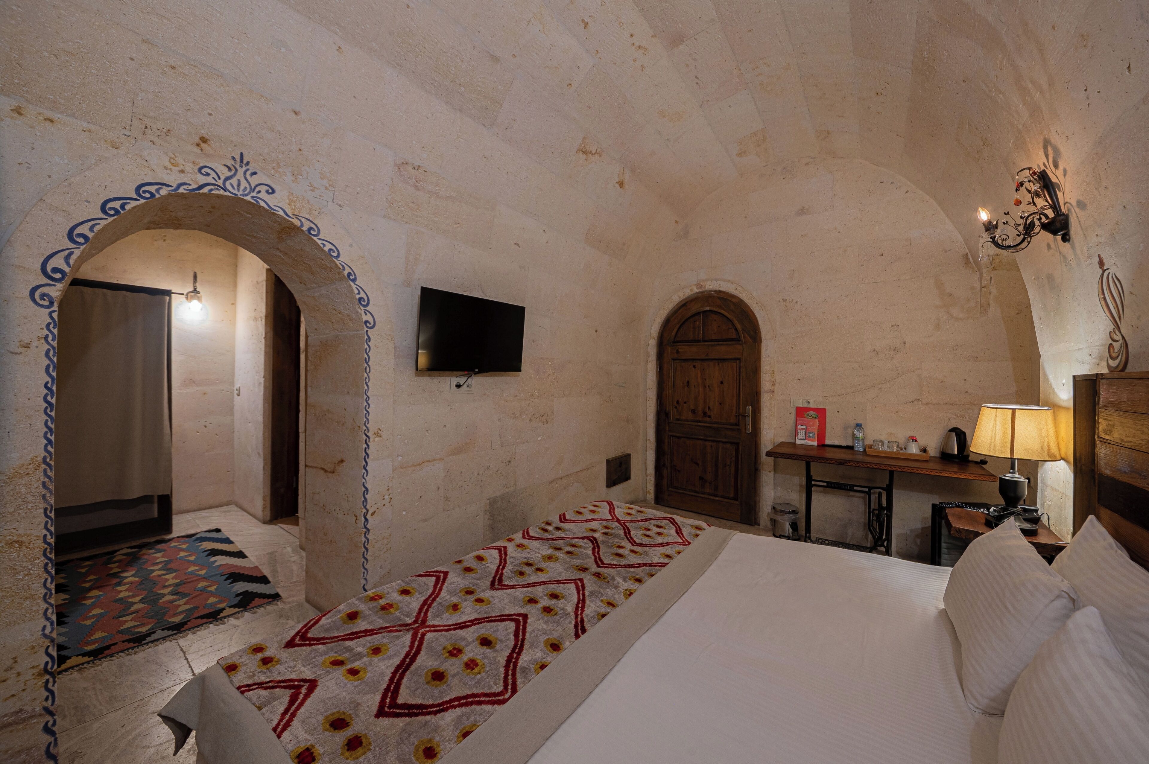 Una habitación con cama, televisión, escritorio y lámpara.