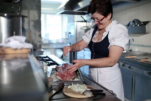 A person preparing food in a kitchen with stainless steel appliances and a window providing natural light.
