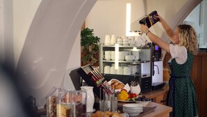 Una mesa de buffet con diversos alimentos, una máquina de café y una persona sirviendo café.