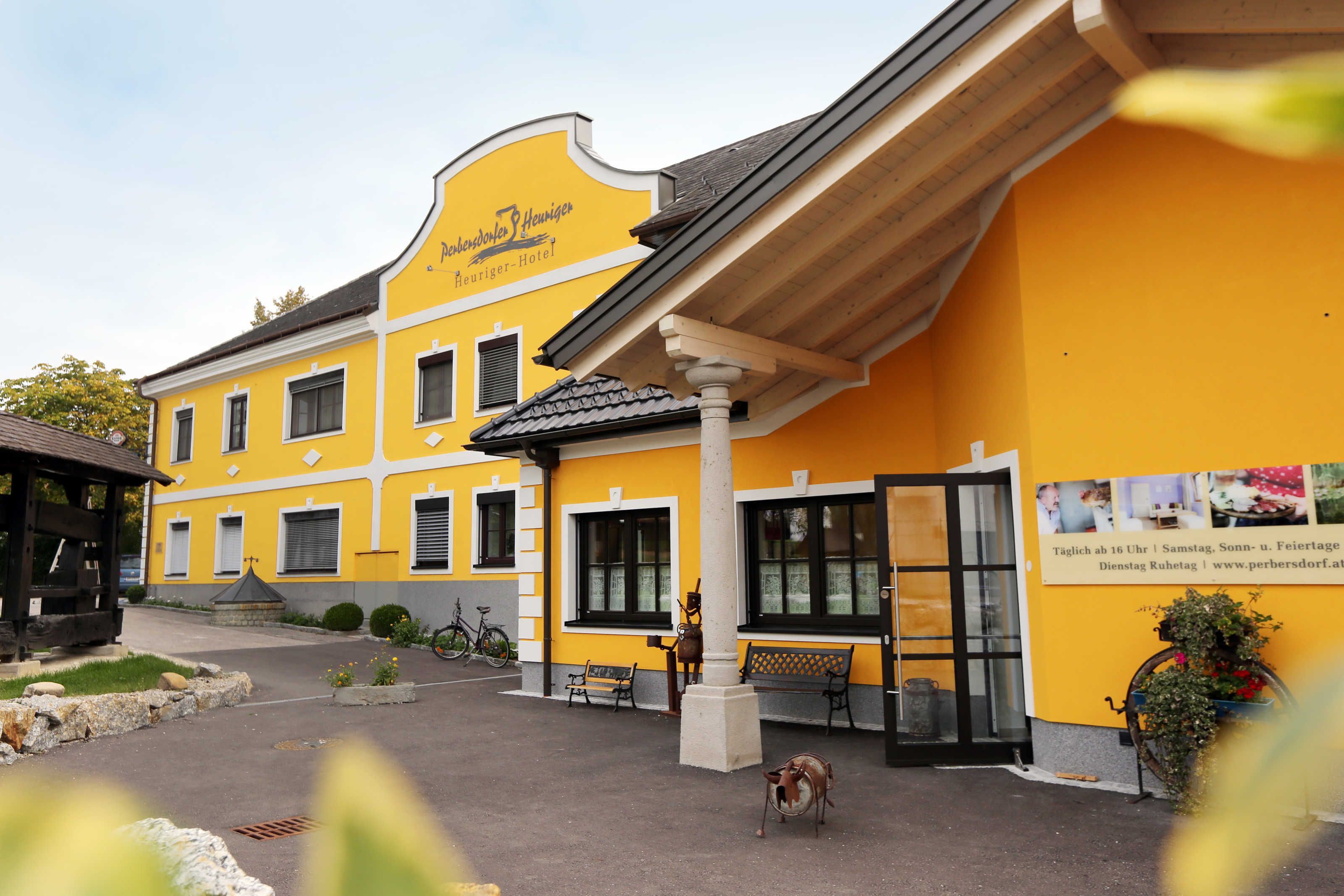 Un bâtiment jaune avec une enseigne indiquant « Hôtel Petersdorf ». On peut voir des bancs à l’extérieur, un vélo et un chien au premier plan.