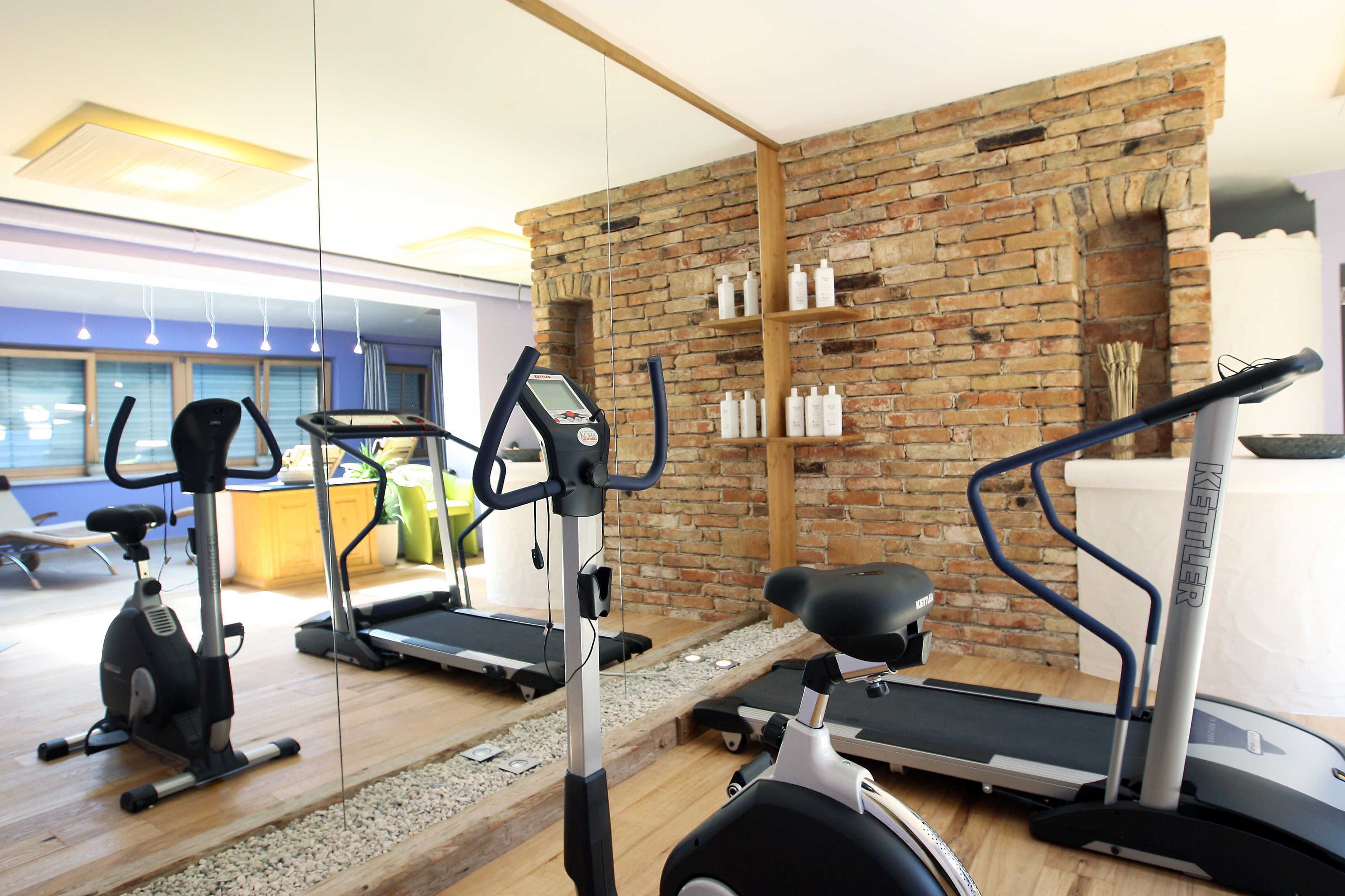 Une salle de sport équipée de matériel d’exercice, avec un mur en briques et un plancher en bois.